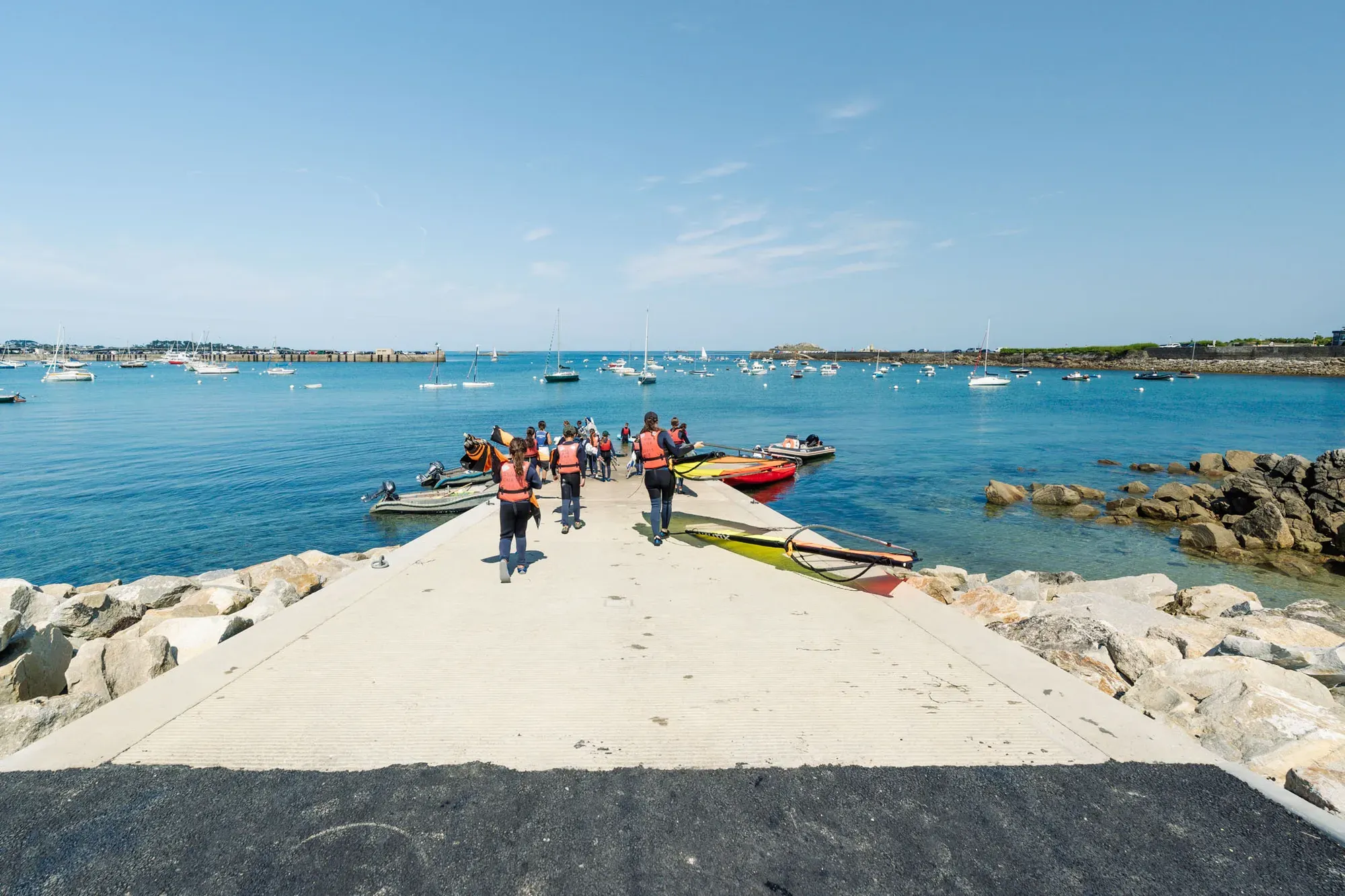Groupe en gilet de sauvetage descendant la cale vers l'eau, kayaks et paddle à proximité